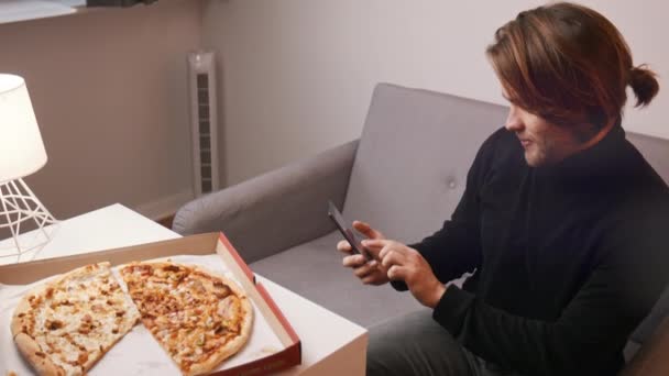 Kafkasyalı genç bir adam akıllı telefonuyla pizza fotoğrafı çekiyor. Yavaş çekim — Stok video