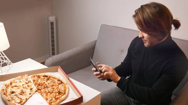 Νεαρός Καυκάσιος έχει παράπονο για πίτσα. Κρατώντας smartphone για να καλέσετε την υποστήριξη πελατών — Φωτογραφία Αρχείου