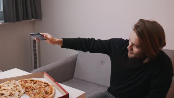 Joven hombre caucásico teniendo una videollamada y mostrando pizza a su familia — Vídeo de stock