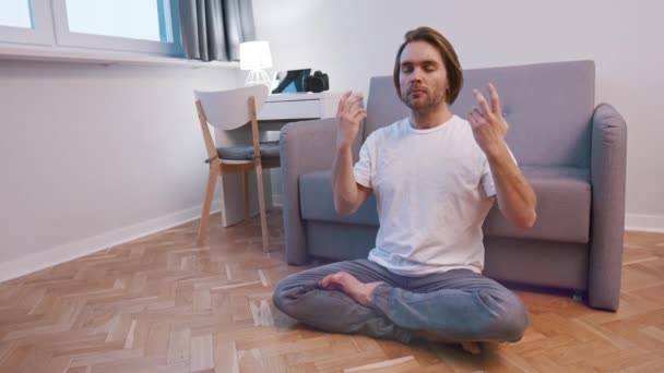 Genç beyaz bir adam dairesinde meditasyon yapıyor. Nefes alma tekniği — Stok video