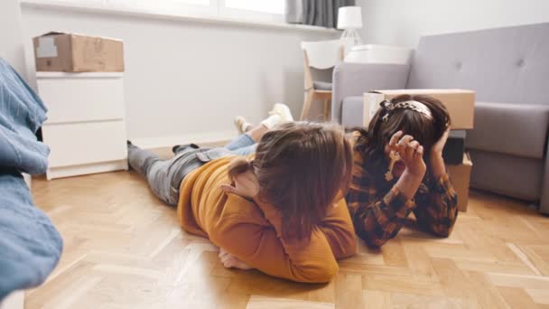 Jong multiraciaal stel dat samenwoont, liggend op de vloer van een nieuw appartement. Het kopen van een nieuwe woning. — Stockvideo