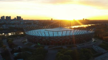 Mor gökyüzü ve altın güneşiyle Varşova Ulusal Stadyumu üzerinde şaşırtıcı bir gün doğumu.
