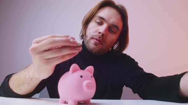 Mann wirft Münze um und legt sie ins Sparschwein. Spar- und Finanzmanagement-Konzept — Stockvideo
