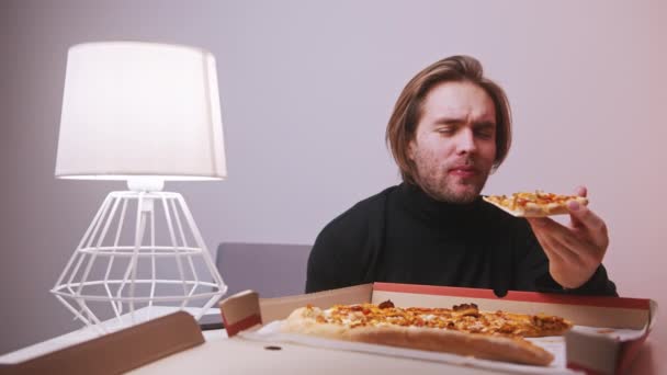 Jovem caucasiano comendo fatia de pizza enquanto tem uma dor de dente — Vídeo de Stock