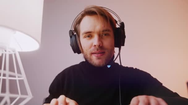 Портрет молодого білоруського чоловіка з навушниками, що грають в ігри на ноутбуці — стокове відео