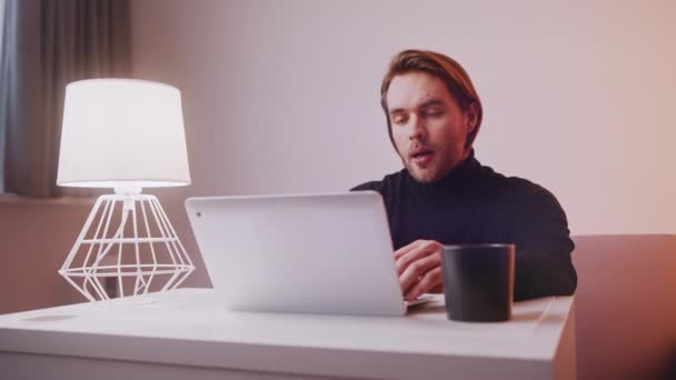 Concepto de trabajo remoto. Joven hombre caucásico teniendo una reunión en línea. Uso de ordenador portátil en casa — Vídeos de Stock