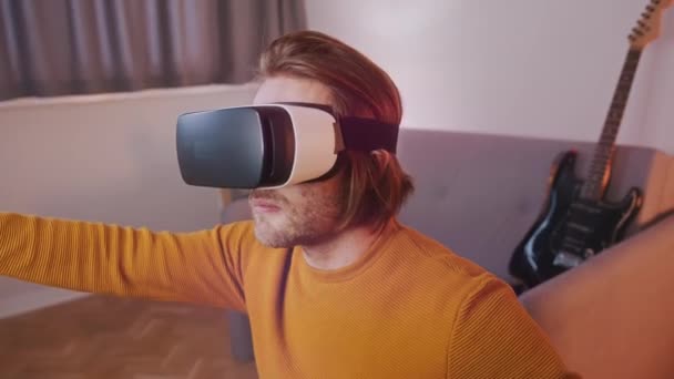 Virtual realitas. Anak muda dengan VR diatur di apartemennya, Gitar di latar belakang — Stok Video