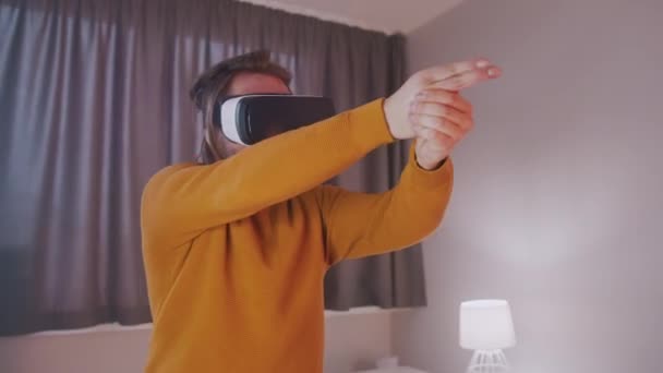 Fiatal férfi VR szemüveggel, aki úgy tesz, mintha lőne a kezével. — Stock videók