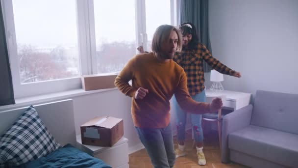 Feliz jovem casal mutiracial dançando no novo apartamento — Vídeo de Stock