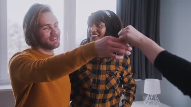 Jeune couple multiracial obtenir les clés de leur nouvelle propriété. Acheteurs de la première maison — Video