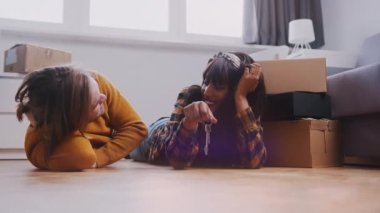 Çok ırklı yeni evli çift yeni evlerinin zemininde yatıyor. Anahtarları elinde tutan kadın
