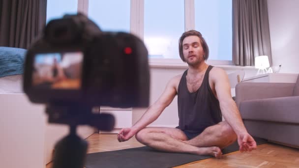 Jeune homme enseignant la méditation et le yoga de la maison. Cours en ligne — Video