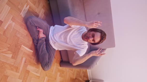 Vertikalt. Ung kaukasisk man mediterar i sin lägenhet. Mindfulness-konceptet — Stockvideo