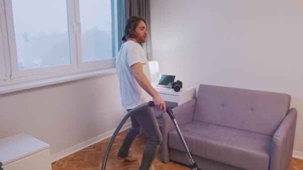 Jovem caucasiano homem limpeza casa e dança ao usar aspirador de pó — Vídeo de Stock
