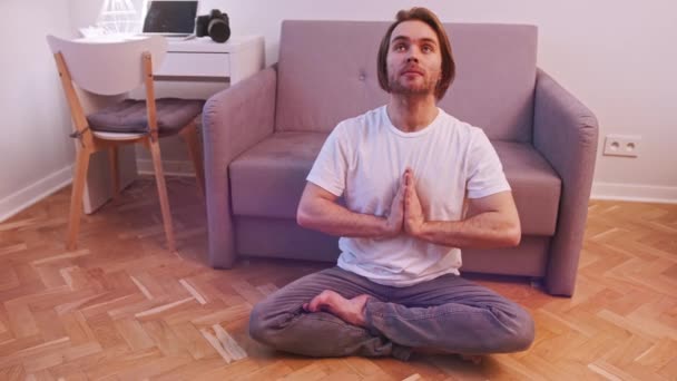 Ung kaukasisk man mediterar i sin lägenhet. Mindfulness-konceptet — Stockvideo