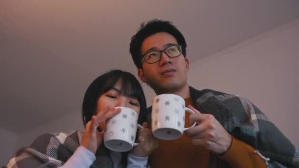 Jeune couple asiatique boire du thé chaud et regarder un film. Amour et concept de famille — Video