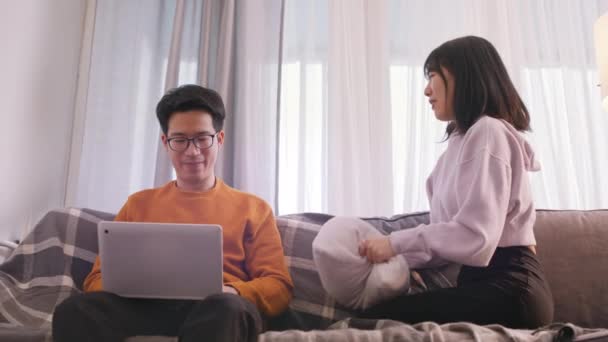 Молодая женщина ищет внимания своего парня, который работает на ноутбуке — стоковое видео