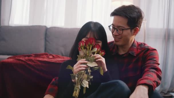 Концепція Дня Святого Валентина або ювілею. Молода жінка пахне червоними трояндами, поки її хлопець цілує і обіймає її — стокове відео