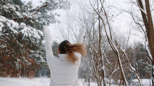 Zbliżenie, młoda kobieta skacząca po pokrytej śniegiem drodze, bawiąca się w parku zimą — Zdjęcie stockowe