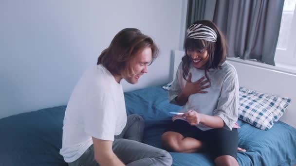 Nadšený šťastný mnohonásobný pár, který se dívá na pozitivní těhotenský test. Noví rodiče objímání a líbání — Stock video