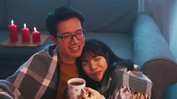 Szczęśliwa młoda para spędzająca razem Walentynki. Przytulając się pod kocem, pijąc kawę ze świecami — Wideo stockowe