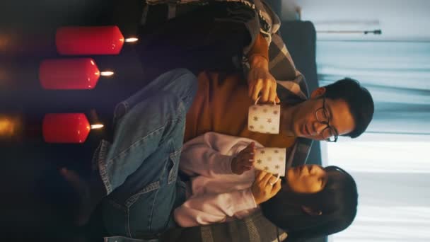 Vertical. feliz asiático pareja pasando calidad tiempo juntos en interior con vela luces cubierto con manta — Vídeos de Stock
