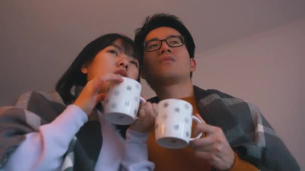 Fiatal ázsiai pár forró teát iszik és filmet néz. Szerelem és szeretet fogalma — Stock videók