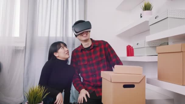 Счастливая молодая пара переезжает вместе. Использование очков VR для просмотра 3D дизайна интерьера — стоковое видео