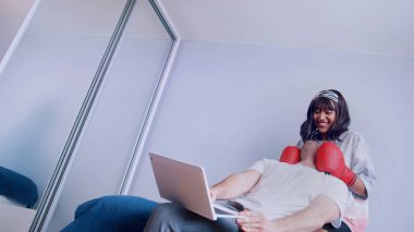 Genç çift yatak odasında eğleniyor. Erkek arkadaşının suratına boks eldiveniyle yumruk atan bir kadın.