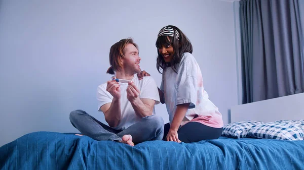 Pareja joven emocionada esperando los resultados de la prueba de embarazo. Prueba positiva. Pareja multiracial esperando un bebé —  Fotos de Stock