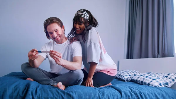 Joyeux jeune couple multiracial qui attend un bébé. Test de grossesse positif — Photo