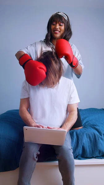 Mulher com luvas de boxe brincando com namorados cabelo longo tentando animá-lo — Fotografia de Stock