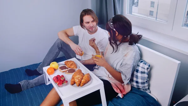 Jeune couple multiracial prenant le petit déjeuner au lit — Photo