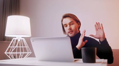 Genç Kafkas öğretmeni laptopta çalışıyor. Yanında da bir fincan kahveyle. Uzaklık öğrenme kavramı