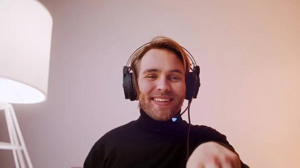 Portrait of young caucasian man with headphones laughing speaking and typing on the laptop keyboard — Stock Photo, Image