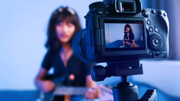 年轻女子在摄像机前弹奏吉他。在线流媒体课程 — 图库照片
