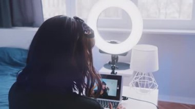 Genç bayan öğretmen yatak odasından yeni bir ders kaydediyor. Modern teknoloji ve internetin sosyal uzaklığı ve kullanımı