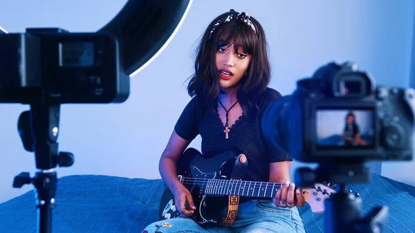 Молодая женщина играет на гитаре перед камерой. запись демонстрации или проведение онлайн-занятий — стоковое фото