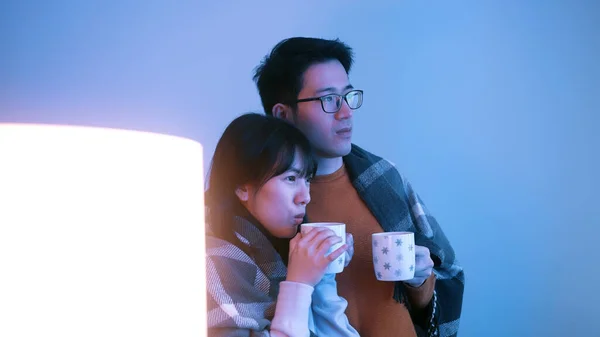 Jovem casal asiático bebendo chá quente e assistindo a um filme. Conceito de amor e afeto — Fotografia de Stock