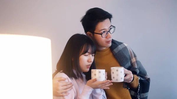 若いアジアのカップルが熱いお茶を飲んで映画を見ています。愛と愛情の概念 — ストック写真