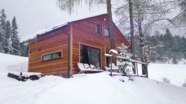 Güzel kış manzarası. Dağda karla kaplı çam ağaçları olan ahşap bir ev. Döndürme çekimi