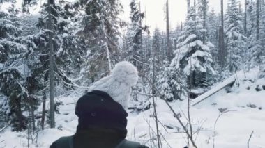 Ormanda güzel bir kar gününde kayak yapan genç bir kadın.