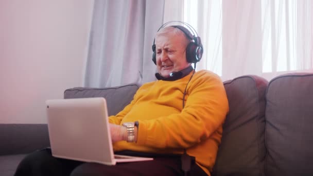 Starší muž se sluchátky ukazující pěst jako hi vyhrává hru — Stock video