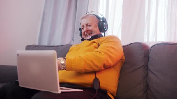 Ευτυχισμένος ηλικιωμένος άνδρας με ακουστικά που κάνει βιντεοκλήση με την οικογένεια — Αρχείο Βίντεο
