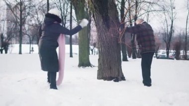 Yaşlı çift parkta kartopu savaşı yapıyor.