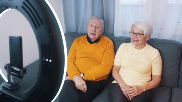 Пожилая пара дает интервью или записывает видео сообщение для семьи — стоковое видео