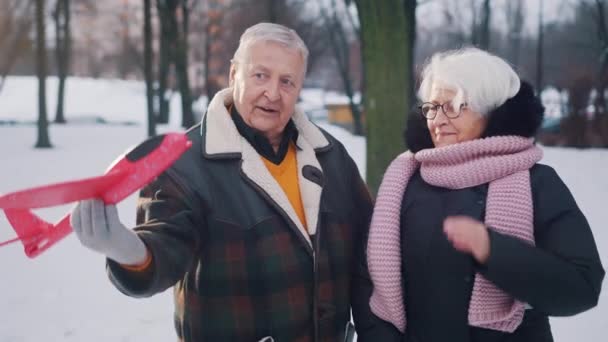 Pasangan lansia merencanakan liburan musim dingin. Man terbang mainan pesawat — Stok Video