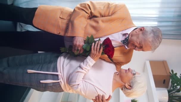 Vertical. Velho surpreendendo sua esposa com um buquê de rosas vermelhas. Aniversário aniversário ou dia dos namorados conceito — Vídeo de Stock