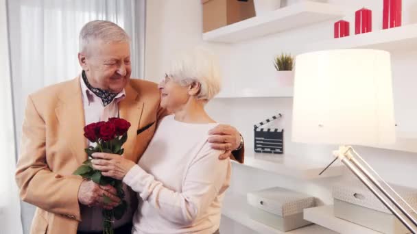 Feliz dia das mães. Casal de idosos comemorando aniversário em casa. Homem dando buquê de rosas vermelhas para sua esposa — Vídeo de Stock