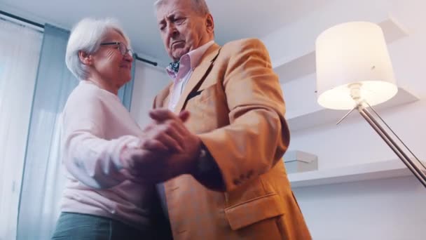 Счастливая пожилая пара на пенсии танцует дома. День рождения, День Святого Валентина или юбилейная концепция — стоковое видео